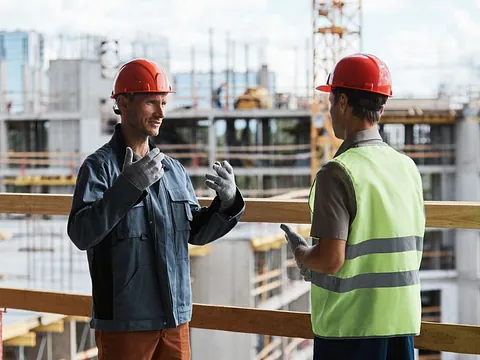 To byggeledere drøfter et projekt på en byggeplads.